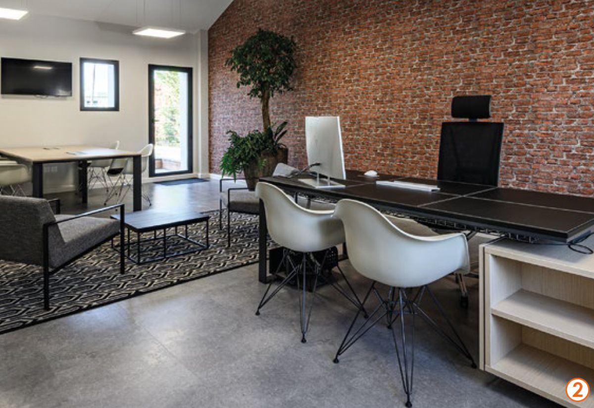 Bureau de direction avec mur en briques rouges, table Eames et fauteuils