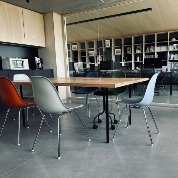 Salle de réunion équipée de chaises Eames colorées et table bois