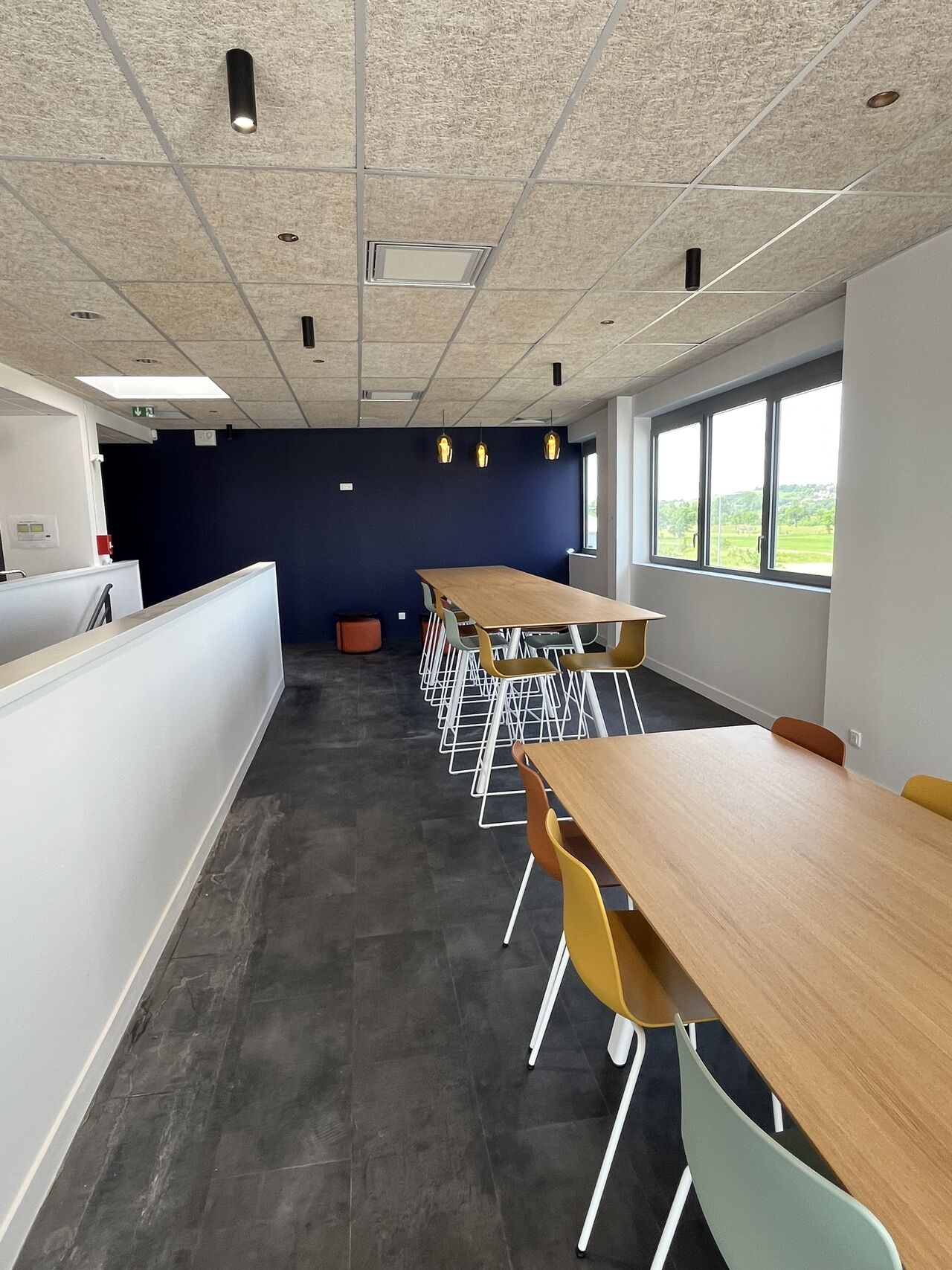 Espace collaboratif aménagé par I Log You, tables hautes bois et assises colorées